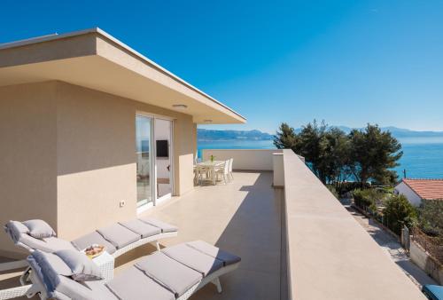 a balcony with white lounge chairs and the ocean at Apartments Alba in Slatine