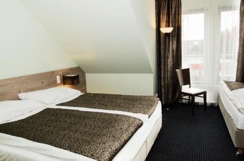 a hotel room with two beds and a chair at Pokoje gościnne WiP in Cieszyn