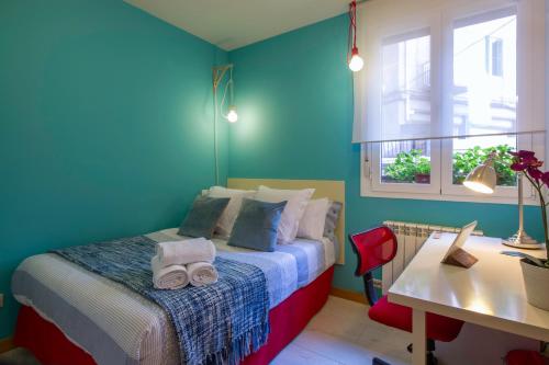 ein Schlafzimmer mit einem Bett mit blauen Wänden und einem Schreibtisch in der Unterkunft Ondarreta Beach Apartment con parking free y Aire acondicionado in San Sebastián