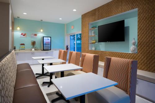 a restaurant with tables and chairs and a flat screen tv at Holiday Inn Express & Suites Nassau by IHG in Nassau