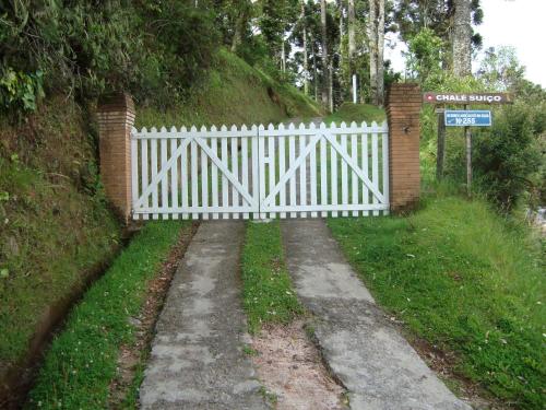 a white fence on a path next to a hill at Chalé Suiço de Campos do Jordão in Campos do Jordão