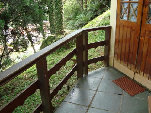 a wooden railing next to a porch with a door at Chalé Suiço de Campos do Jordão in Campos do Jordão