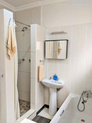 a white bathroom with a sink and a shower at Home Up Guest Apartments and Lodge in Blantyre