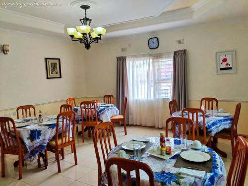 comedor con mesas y sillas y reloj en Home Up Guest Apartments and Lodge, en Blantyre
