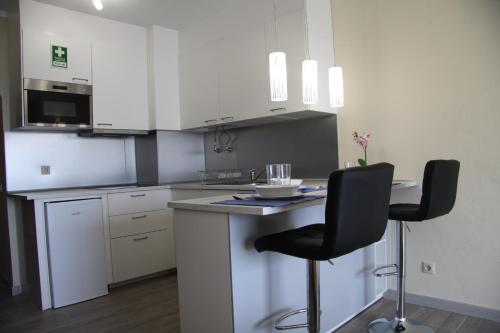 a kitchen with white cabinets and two black chairs at Estrela do Mar in Albufeira