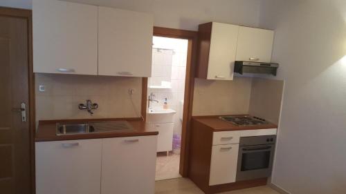 a small kitchen with white cabinets and a sink at Apartments Vlasic in Ston
