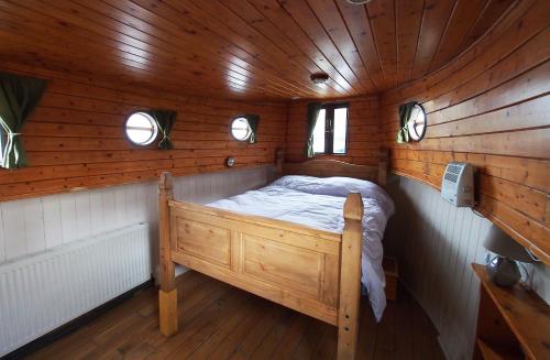 Roisin Dubh Houseboat في Sallins: غرفة نوم في كابينة خشب فيها سرير