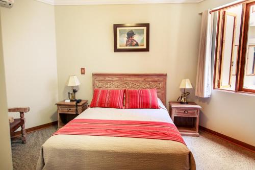 a bedroom with a large bed with red pillows at Hotel Antigua Miraflores in Lima