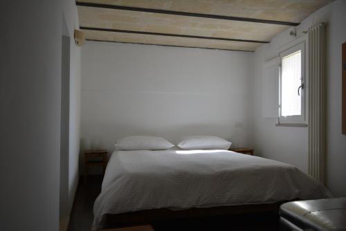 a bedroom with a bed with white sheets and a window at San Biagio Materapartment in Matera