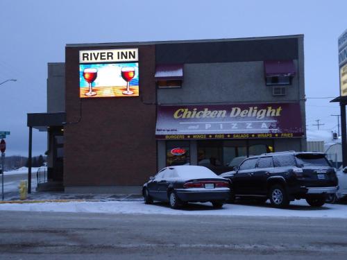 two cars parked in a parking lot outside of a restaurant at River Inn in Nipawin