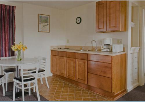 a kitchen with a sink and a table with chairs at Sands By The Sea Motel in York Beach