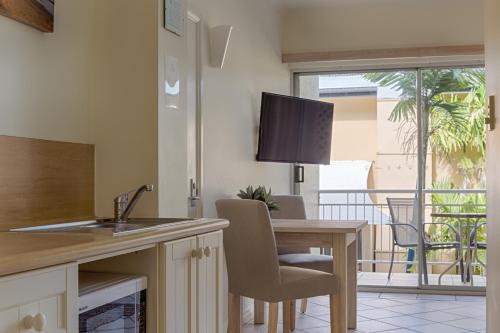 a kitchen with a table and a dining room with a balcony at Macrossan House Boutique Holiday Apartments in Port Douglas