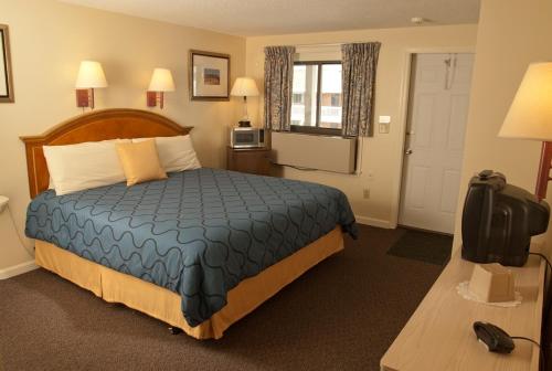 a hotel room with a bed with a blue comforter at Sands By The Sea Motel in York Beach