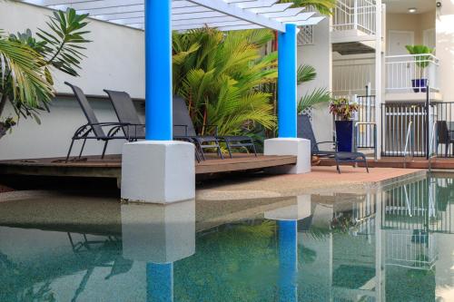 a patio with chairs and a swimming pool at Macrossan House Boutique Holiday Apartments in Port Douglas