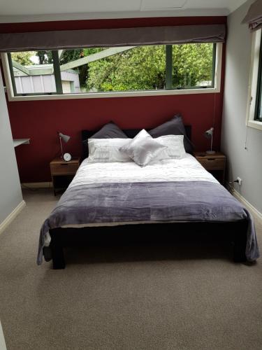 a bedroom with a large bed with a large window at Central Taupo Townhouse in Taupo
