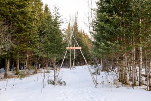 a sign in the middle of a snow covered forest at Aux Pignons Rouges Camping & Chalets in Saint Romain
