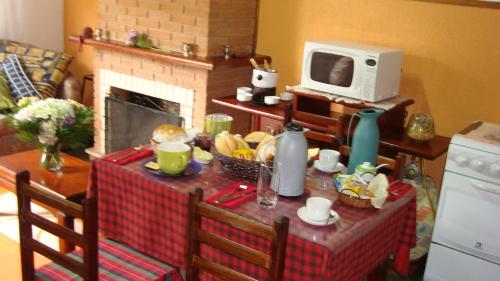 a kitchen with a table with a microwave and a table with food at Chalé Suiço de Campos do Jordão in Campos do Jordão
