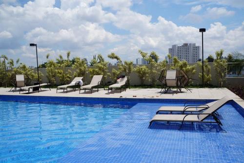 una piscina con tumbonas y sillas en un edificio en Conforto no Alto da Boa Vista, en São Paulo