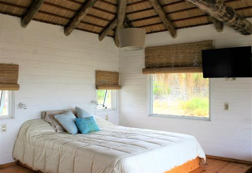 a bedroom with a bed in a room with windows at Cabaña PRAIA in Punta Del Diablo