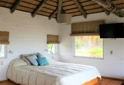una camera da letto con un letto in una stanza con finestre di Cabaña PRAIA a Punta Del Diablo