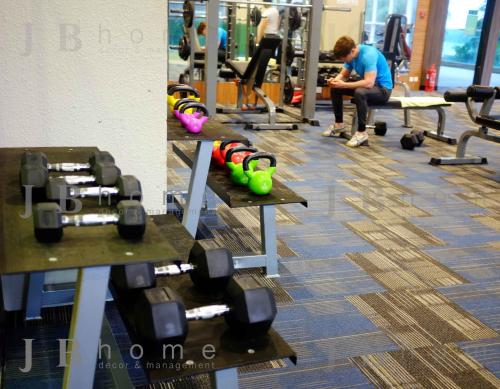 a man sitting on a bench in a gym with weights at Paragon Residences Straits View Homestay by WELCOME HOME in Johor Bahru