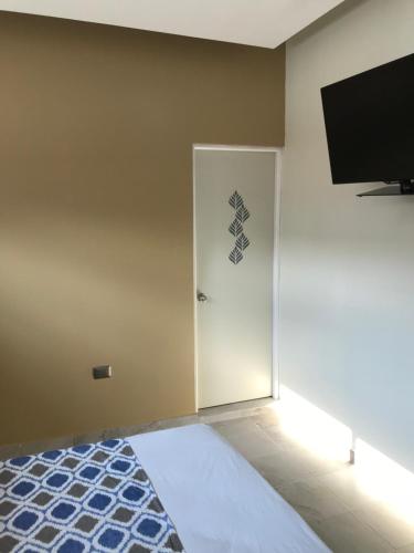 a room with a door with a television and a bed at Hotel Plaza Amalia in Tuxtla Gutiérrez