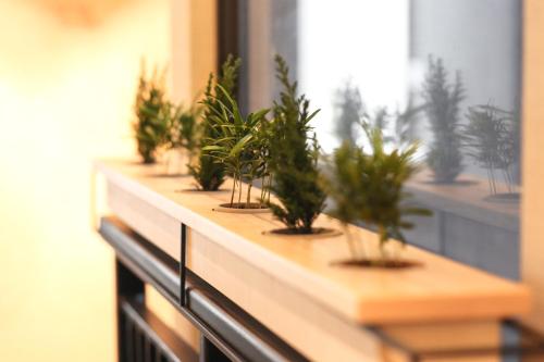 una fila de plantas en macetas sentadas en el alféizar de una ventana en Hotel Ease Access Tsuen Wan en Hong Kong