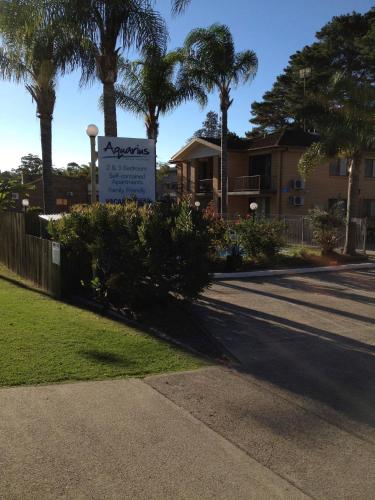 a sign in front of a house with palm trees at Aquarius Batehaven in Batemans Bay