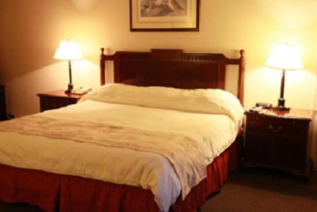 a bed in a hotel room with two lamps on tables at Caravelle Inn Extended Stay in San Jose