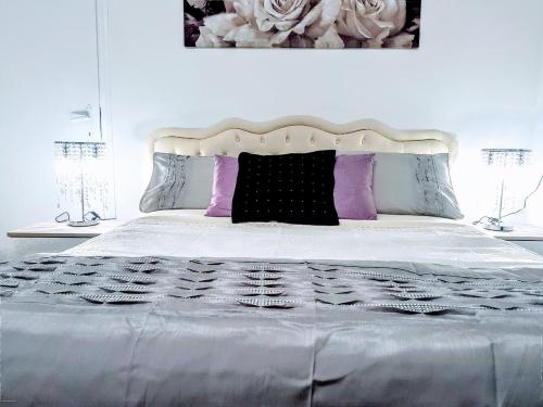 un letto bianco con cuscini viola e neri sopra di B&B Vanessa House a Martellago