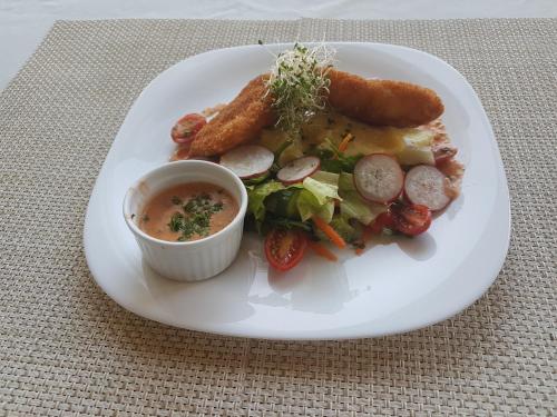 a plate of food with sausage and vegetables and dipping sauce at Caribbean Diamond Boutique Hotel in Sosúa