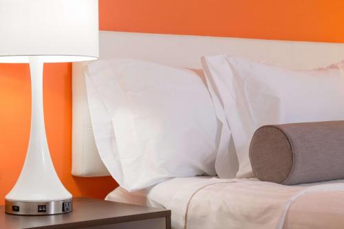 a bed with white pillows and a table with a lamp at Howard Johnson by Wyndham Toms River in Toms River