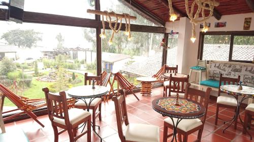 a restaurant with tables and chairs and a large window at Villa Mimi in Otavalo