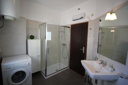 uma casa de banho com uma máquina de lavar roupa e um lavatório em Villa Jadrana em Rab