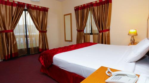 a hotel room with a bed and a phone on a desk at Al Shorouq Hotel Apartments in Muscat