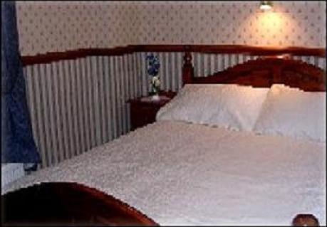 a bedroom with a white bed with a wooden headboard at Dover's Restover Bed & Breakfast in Dover