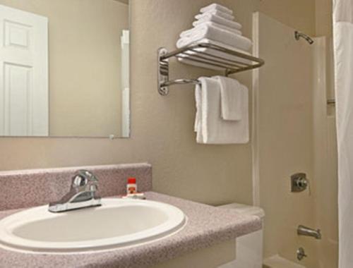 y baño con lavabo, espejo y toallas. en Super 8 by Wyndham Sacramento/Florin Rd en Sacramento