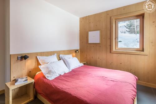 a bedroom with a red bed with a window at Le Refuge de Montgésin in Aime-La Plagne