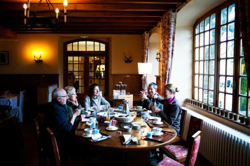 a group of people sitting around a table in a restaurant at La Domerie - Maison d'hôtes in Aubrac