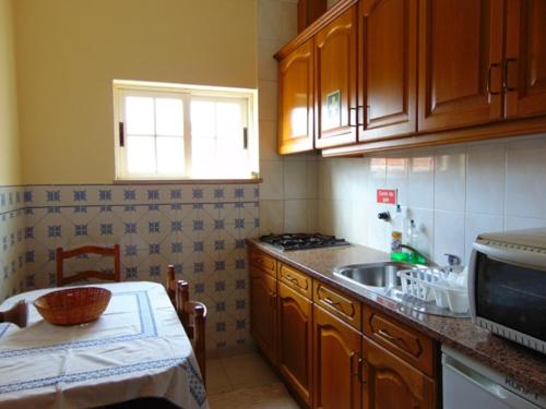 a kitchen with wooden cabinets and a sink and a table at Saraiva's Guest House in Lagos