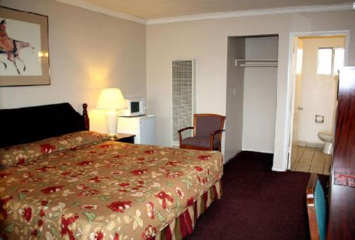 a hotel room with a bed and a table and chair at Sunset Inn and Suites West Sacramento in West Sacramento