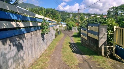 a fence and a dirt road next to a wall at Les Bungalows du Mont-Auban in Sainte-Clotilde