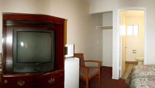 a hotel room with a television and a bed at Sunset Inn and Suites West Sacramento in West Sacramento