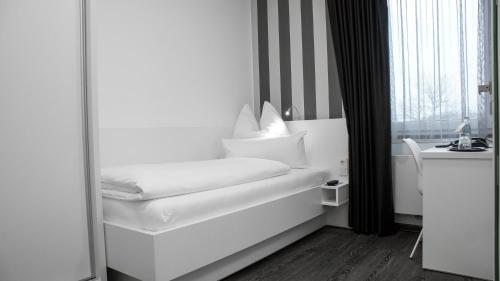 a white bed in a room with a window at OK Das Businesshotel in Braunschweig