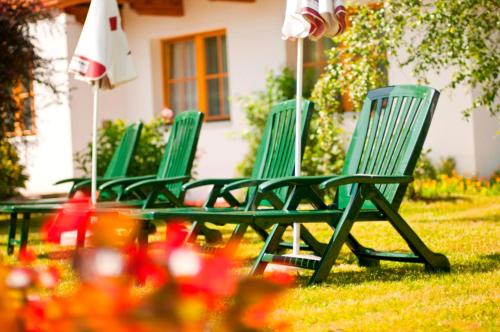 three green lawn chairs sitting in the grass at Hotel - Restaurant Platzwirt in Rauris