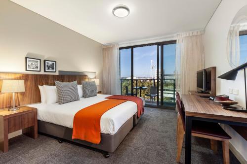a bedroom with a bed and a desk with a computer at Quest at Sydney Olympic Park in Sydney