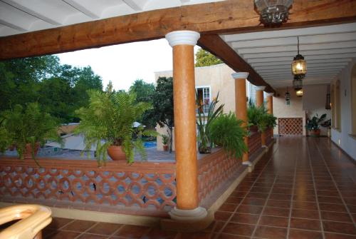 a porch with columns and potted plants and a pool at Hotel Boutique La Granja in Tequisquiapan