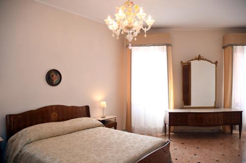 een slaapkamer met een bed, een spiegel en een kroonluchter bij Residenza Ca Trinità in Venetië