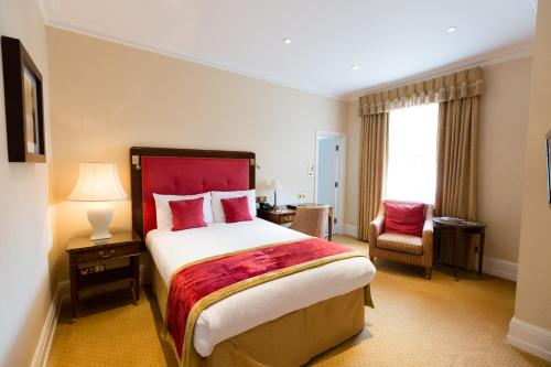 a hotel room with a large bed and a chair at The Spa Hotel in Royal Tunbridge Wells