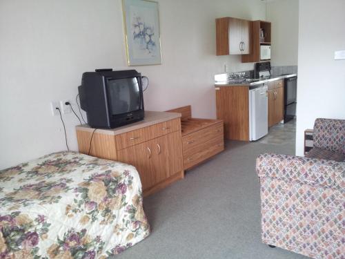 una camera d'albergo con TV, letto e cucina di Ace High Motor Inn a Napier